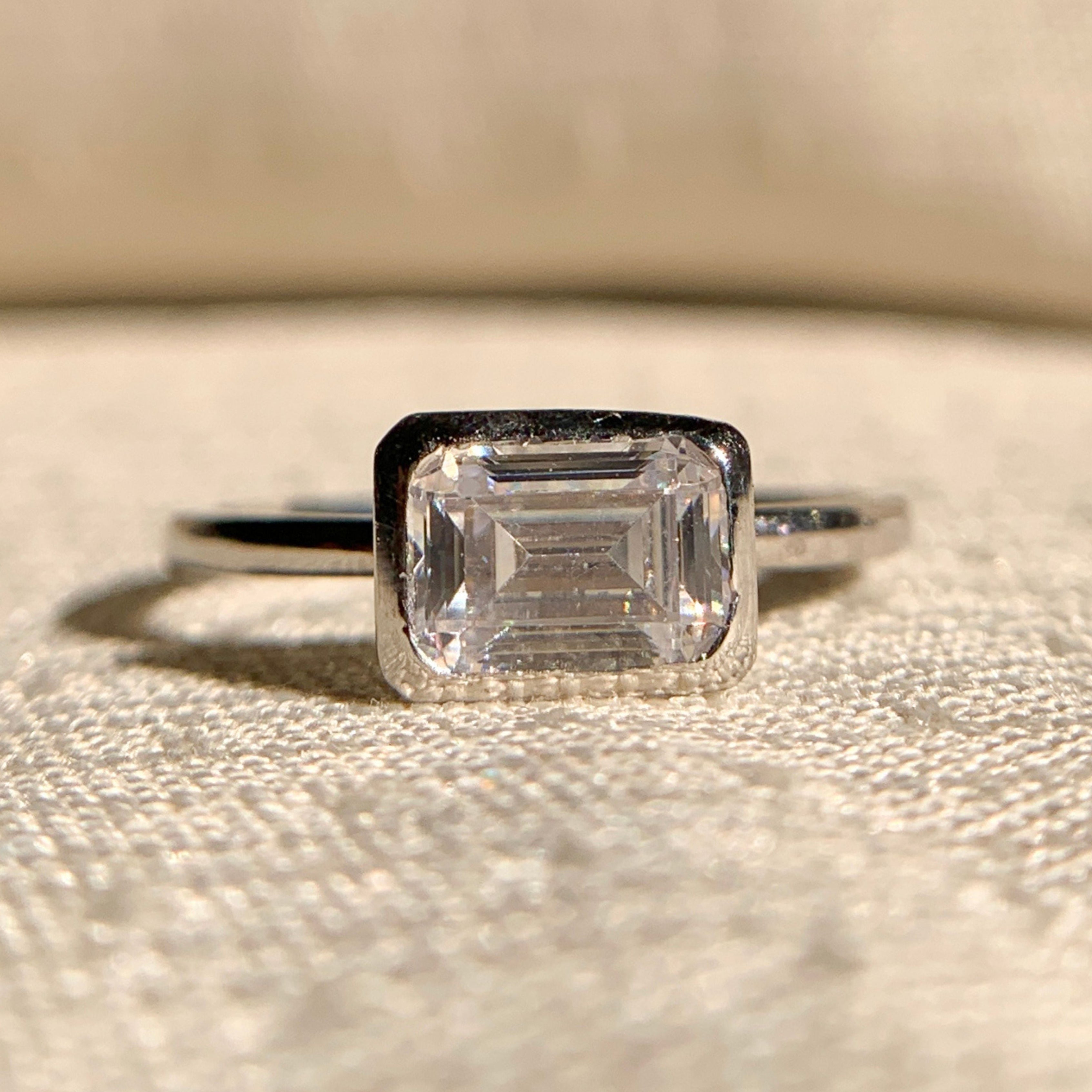 “Emerald cut east-west solitaire engagement ring in sleek white gold setting”